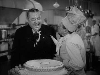 Movie still from “The Lady Eve” (1941), directed by Preston Sturges – A black - and - white photo of a man and a woman cutting a cake; Medium shot, Over the shoulder angle