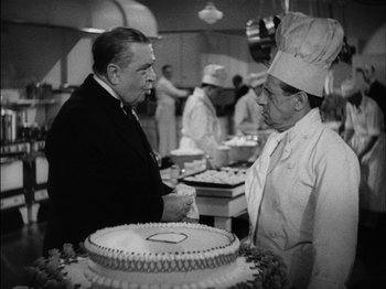 Movie still from “The Lady Eve” (1941), directed by Preston Sturges – Two men in a kitchen with a cake on the counter; Medium shot, Over the shoulder angle