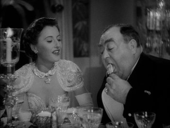 Movie still from “The Lady Eve” (1941), directed by Preston Sturges – An old photo of a man and a woman at a dinner table; Medium shot, High angle
