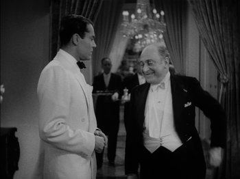 Movie still from “The Lady Eve” (1941), directed by Preston Sturges – Two men in tuxedos talking to each other in a hallway; Medium shot, Over the shoulder angle
