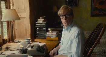 Movie still from “The Lady in the Van” (2015), directed by Nicholas Hytner – A man sitting in front of a typewriter in front of a stack of books; Medium shot, High angle