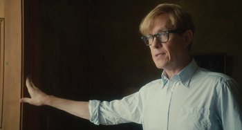 Movie still from “The Lady in the Van” (2015), directed by Nicholas Hytner – A man in a white shirt and glasses is pointing; Close Up shot, Over the shoulder angle