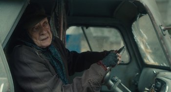 Movie still from “The Lady in the Van” (2015), directed by Nicholas Hytner – An old man driving a car while holding a cell phone; Close Up shot, High angle