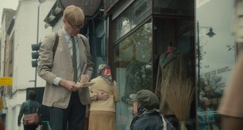 Movie still from “The Lady in the Van” (2015), directed by Nicholas Hytner – A man standing next to a woman in front of a building; Medium shot, Over the shoulder angle