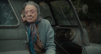 Movie still from “The Lady in the Van” (2015), directed by Nicholas Hytner – An older woman sitting in a car with a scarf around her neck; Close Up shot, Over the shoulder angle