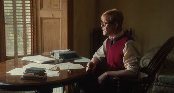 Movie still from “The Lady in the Van” (2015), directed by Nicholas Hytner – A man sitting at a table with a typewriter; Medium shot, Over the shoulder angle