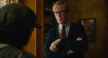 Movie still from “The Lady in the Van” (2015), directed by Nicholas Hytner – A man wearing glasses and a red neck tie standing in front of another man; Medium shot, Over the shoulder angle