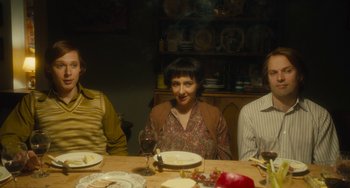 Movie still from “The Lady in the Van” (2015), directed by Nicholas Hytner – A woman sitting at a table with two other people; Medium shot, High angle
