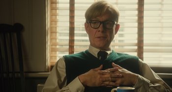 Movie still from “The Lady in the Van” (2015), directed by Nicholas Hytner – An older man wearing glasses and a tie; Medium shot, Over the shoulder angle