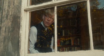 Movie still from “The Lady in the Van” (2015), directed by Nicholas Hytner – A man wearing glasses looking out of a window; Medium shot, Over the shoulder angle
