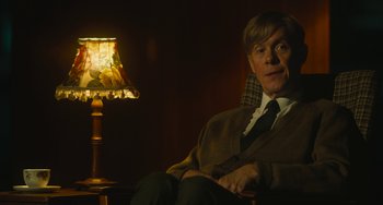 Movie still from “The Lady in the Van” (2015), directed by Nicholas Hytner – A man sitting in a chair next to a table lamp; Medium shot, Over the shoulder angle