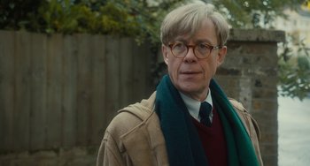Movie still from “The Lady in the Van” (2015), directed by Nicholas Hytner – An older man wearing glasses and wearing a sweater and a scarf; Close Up shot, Over the shoulder angle