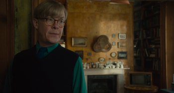 Movie still from “The Lady in the Van” (2015), directed by Nicholas Hytner – A man in a room with a fireplace and mantle; Medium shot, Over the shoulder angle