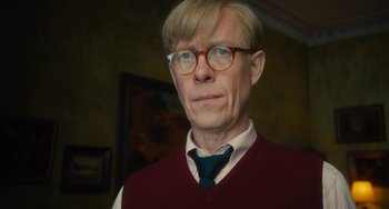 Movie still from “The Lady in the Van” (2015), directed by Nicholas Hytner – A person wearing glasses and a tie; Close Up shot, Low angle