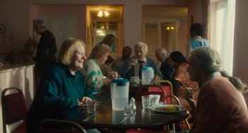 Movie still from “The Lady in the Van” (2015), directed by Nicholas Hytner – A group of people sitting around a table; Wide shot, Over the shoulder angle