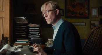 Movie still from “The Lady in the Van” (2015), directed by Nicholas Hytner – An older man in glasses using a cell phone in a cluttered room; Medium shot, Low angle