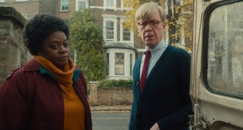 Movie still from “The Lady in the Van” (2015), directed by Nicholas Hytner – A man and a woman standing next to each other on the street; Medium shot, Over the shoulder angle