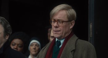 Movie still from “The Lady in the Van” (2015), directed by Nicholas Hytner – An older man wearing glasses and a tie; Close Up shot, Over the shoulder angle