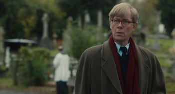 Movie still from “The Lady in the Van” (2015), directed by Nicholas Hytner – A man in a suit and tie standing in front of a tree; Close Up shot, Over the shoulder angle