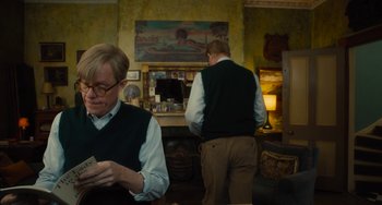 Movie still from “The Lady in the Van” (2015), directed by Nicholas Hytner – Two men in a room with a fireplace and a painting on the wall behind them; Medium shot, Over the shoulder angle