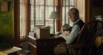 Movie still from “The Lady in the Van” (2015), directed by Nicholas Hytner – An older man sitting at a desk in front of a window; Medium shot, Over the shoulder angle