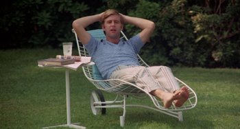 Movie still from “The Landlord” (1970), directed by Hal Ashby – A man sitting in a lawn chair on the grass; Medium shot, High angle