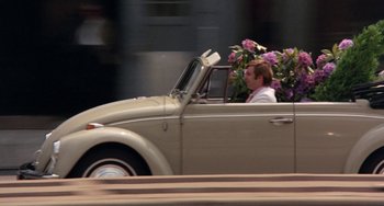 Movie still from “The Landlord” (1970), directed by Hal Ashby – A man driving a volkswagon beetle car with flowers in the back seat; Wide shot, High angle