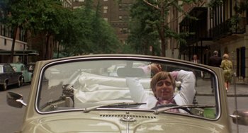 Movie still from “The Landlord” (1970), directed by Hal Ashby – A man in a car with his hands behind his head; Medium shot, High angle