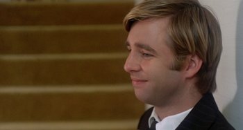Movie still from “The Landlord” (1970), directed by Hal Ashby – A young man with blonde hair and a suit and tie; Close Up shot, Over the shoulder angle