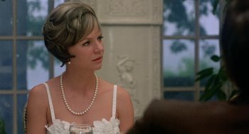 Movie still from “The Landlord” (1970), directed by Hal Ashby – A woman in a white dress with a pearl necklace; Close Up shot, Over the shoulder angle