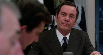Movie still from “The Landlord” (1970), directed by Hal Ashby – A man wearing a suit and tie sitting at a table; Close Up shot, Over the shoulder angle