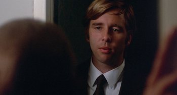 Movie still from “The Landlord” (1970), directed by Hal Ashby – A man wearing a suit and tie looking at the camera; Close Up shot, Over the shoulder angle