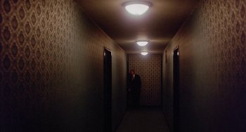 Movie still from “The Landlord” (1970), directed by Hal Ashby – A man in a suit standing in a dark hallway; Wide shot, High angle