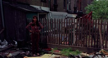 Movie still from “The Landlord” (1970), directed by Hal Ashby – A woman standing in front of a wooden fence; Wide shot, High angle