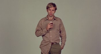 Movie still from “The Landlord” (1970), directed by Hal Ashby – A young man holding a drink in his hand; Medium shot, High angle
