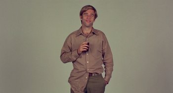 Movie still from “The Landlord” (1970), directed by Hal Ashby – A man in a brown shirt is holding a beer; Medium shot, Low angle