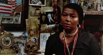 Movie still from “The Landlord” (1970), directed by Hal Ashby – An older woman wearing a black shirt and red necklace; Close Up shot, Over the shoulder angle