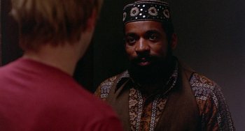 Movie still from “The Landlord” (1970), directed by Hal Ashby – A man with a beard wearing a hat looking into a mirror; Close Up shot, Over the shoulder angle