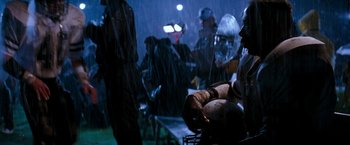 Movie still from “The Last Boy Scout” (1991), directed by Tony Scott – A group of people standing in the rain next to a table; Medium shot, High angle