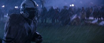 Movie still from “The Last Boy Scout” (1991), directed by Tony Scott – A group of people in a field with a football helmet on; Close Up shot, Over the shoulder angle