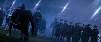 Movie still from “The Last Boy Scout” (1991), directed by Tony Scott – A group of men walking across a football field in the rain; Wide shot, Low angle