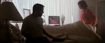 Movie still from “The Last Boy Scout” (1991), directed by Tony Scott – A man sitting on a couch in front of a television; Medium shot, Over the shoulder angle