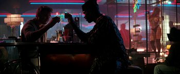 Movie still from “The Last Boy Scout” (1991), directed by Tony Scott – A man sitting at a bar looking at his cell phone; Medium shot, Over the shoulder angle