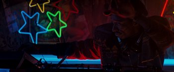 Movie still from “The Last Boy Scout” (1991), directed by Tony Scott – A man in a sweater is using a dj controller in front of neon lights; Medium shot, Low angle