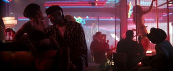 Movie still from “The Last Boy Scout” (1991), directed by Tony Scott – A group of people sitting in a room with lights in the background; Medium shot, Low angle