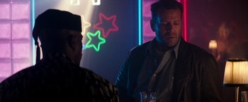 Movie still from “The Last Boy Scout” (1991), directed by Tony Scott – A man standing next to another man holding a glass; Medium shot, Over the shoulder angle