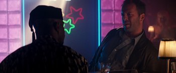 Movie still from “The Last Boy Scout” (1991), directed by Tony Scott – Two men are standing in a room with neon lights in the background; Medium shot, Over the shoulder angle