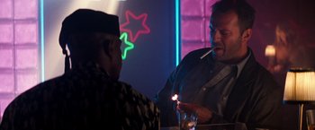 Movie still from “The Last Boy Scout” (1991), directed by Tony Scott – A man is lighting a cigarette at a bar; Medium shot, Over the shoulder angle
