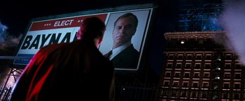 Movie still from “The Last Boy Scout” (1991), directed by Tony Scott – A man standing in front of a large poster of a man; Medium shot, Low angle