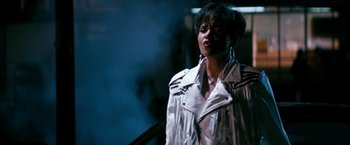 Movie still from “The Last Boy Scout” (1991), directed by Tony Scott – A woman in a white jacket standing in front of a building; Medium shot, High angle